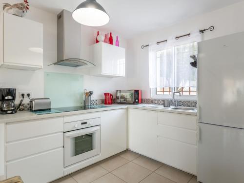 une cuisine blanche avec des armoires blanches et un réfrigérateur dans l'établissement Holiday Home A la porte d'Avignon by Interhome, à Laudun-l'Ardoise