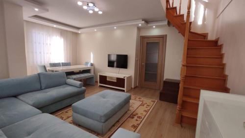 a living room with a blue couch and a staircase at Duplex 41 in the city center of Umraniye Alemdag caddesi Istanbul in Sarıgazi