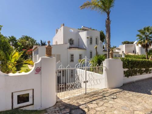 ヴィラモウラにあるVilla Villa Verde by Interhomeの門とヤシの木がある白い家