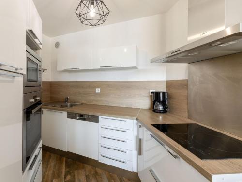 a small kitchen with white cabinets and a sink at Apartment le Grand Foc-1 by Interhome in Capbreton