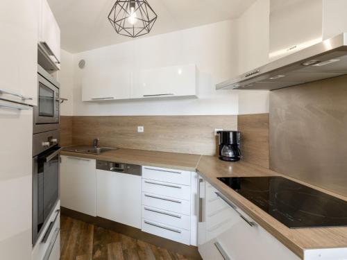 Una pequeña cocina con gabinetes blancos y un fregadero. en Apartment le Grand Foc-1 by Interhome, en Capbreton