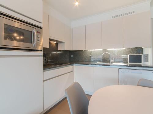 a white kitchen with a table and a microwave at Apartment Sea Breeze by Interhome in Bredene