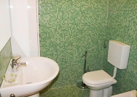 a green tiled bathroom with a toilet and a sink at Volturnus a soli 150m dal mare con WI FI in Marina di Castagneto Carducci