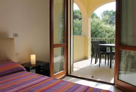 a bedroom with a bed and a balcony with a table at Volturnus a soli 150m dal mare con WI FI in Marina di Castagneto Carducci
