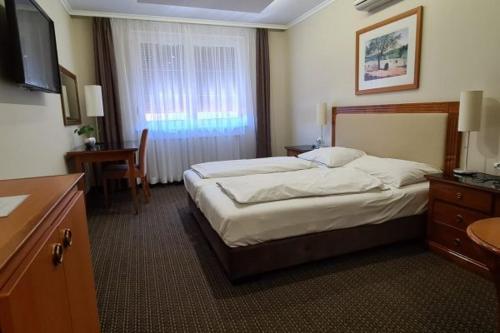 ein Hotelzimmer mit einem großen Bett und einem Schreibtisch in der Unterkunft Korona Panzió in Hatvan