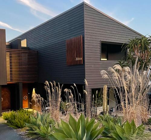 a black house with plants in front of it at Hyams Beach House A - Brand new lux beach Oasis in Hyams Beach