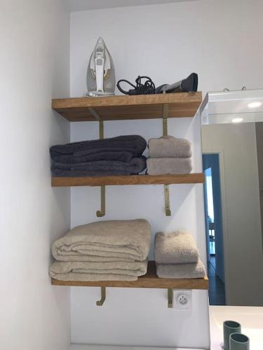 Cette chambre dispose d'étagères en bois, de serviettes et d'un miroir. dans l'établissement Superbe appartement très confortable, à Serris