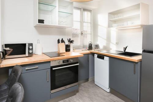 une cuisine avec des armoires blanches et un comptoir en bois dans l'établissement N3 des Études Duplex Hypercentre Wifi ConciergerieDameCarcas, à Carcassonne