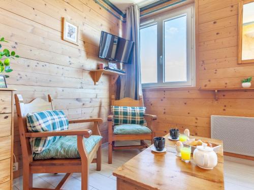 un salon avec une table, des chaises et une télévision dans l'établissement Apartment Baikonour-7 by Interhome, au Corbier