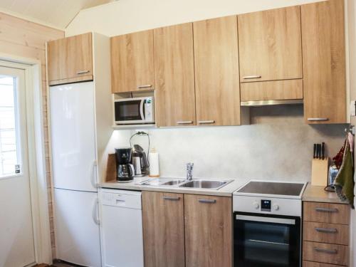eine Küche mit Holzschränken und einem weißen Kühlschrank in der Unterkunft Holiday Home Isohukka by Interhome in Hyrynsalmi