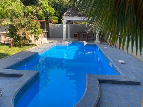 a swimming pool with blue water in a backyard at Queen Zee Garden Apartments in Kololi
