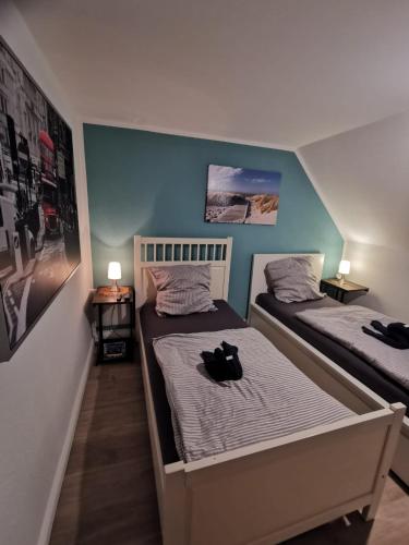 ヴィルヘルムスハーフェンにあるMansarde Ferienwohnung - Modern - Zentral - PayTVのベッドルーム1室(ベッド2台、黒猫がベッドに座っている)