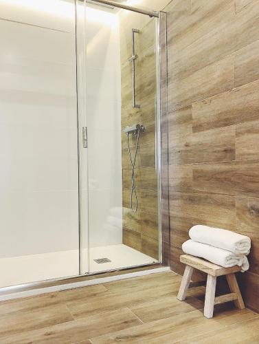 a bathroom with a shower and a stool with towels at Apartamentos La Gloria in Benidorm