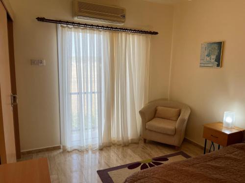 a bedroom with a bed and a chair and a window at Seaview apartment with roof terrace in Kalecik