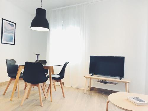 a living room with a table with chairs and a television at Apartamentos La Gloria in Benidorm