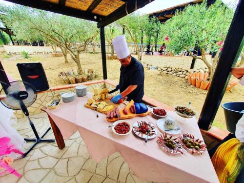 Um homem de chapéu de chefs a preparar comida numa mesa. em Villa Parco Morello Piano Terra em Villarosa
