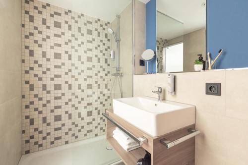 a bathroom with a sink and a shower at acora Augsburg Living the City in Neusäß