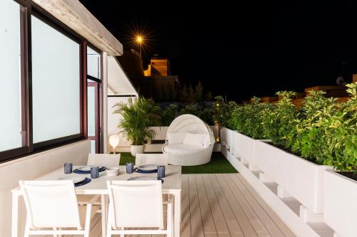 a balcony with white tables and chairs and plants at The Terraces Luxury Penthouses, 3D in Santa Cruz de Tenerife