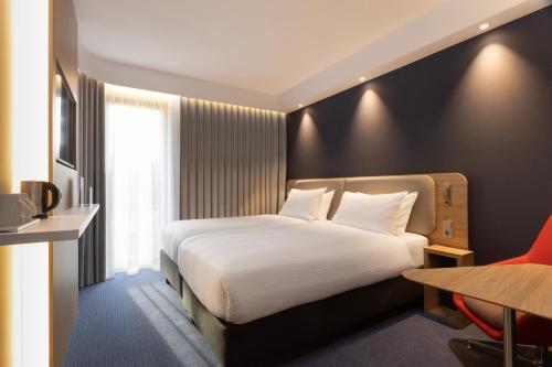 - une chambre avec un grand lit blanc et un bureau dans l'établissement Holiday Inn Express & Suites - Deventer, an IHG Hotel, à Deventer