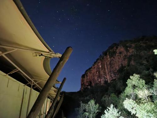 a tent with a view of a mountain at night at Mbizane Escarpment Retreat in Schoemanskloof