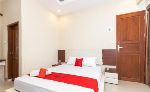 a bedroom with a large bed with red pillows at RedDoorz Syariah @ Batua Raya in Makassar
