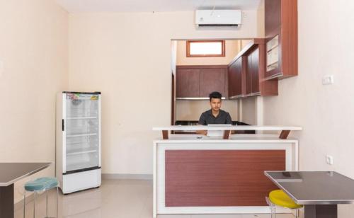 a man sitting at a counter in a kitchen at RedDoorz Syariah @ Batua Raya in Makassar