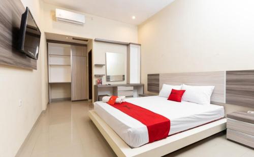 una camera con un grande letto e una televisione di RedDoorz Syariah @ Batua Raya a Makassar