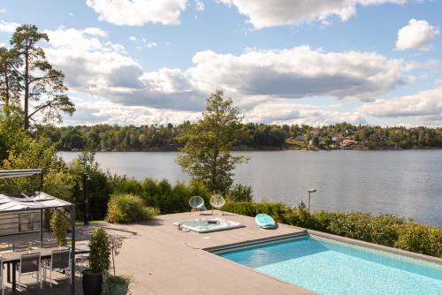 a swimming pool with a view of a lake at Exclusive Lakefront Mansion with pools in Stockholm in Tyresö