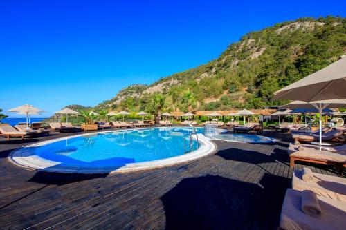 a swimming pool with chairs and umbrellas at a resort at Manaspark Deluxe Hotel in Oludeniz