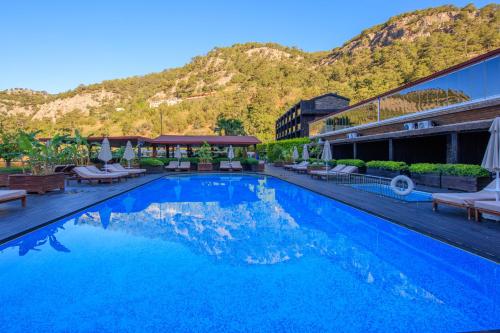 a large swimming pool with a mountain in the background at Manaspark Deluxe Hotel in Oludeniz