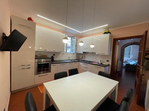 cocina con mesa blanca, mesa y sillas en La Casa Di Emma, en Lucca