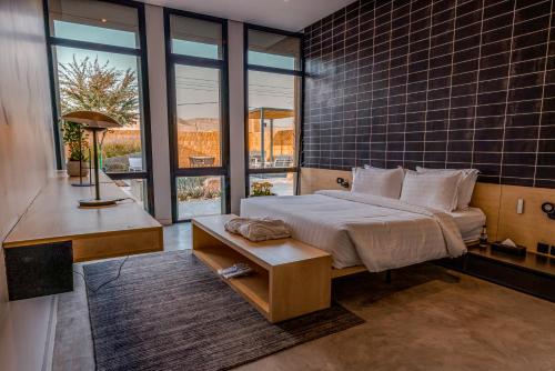 a bedroom with a bed and a desk and windows at Najdarah Resort in Riyadh