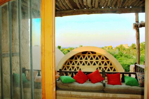 a window with a couch with red and green pillows at Tunis Lake View in ‘Izbat an Nāmūs