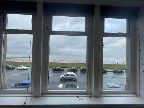 a window with a view of a parking lot with cars at The Clarendon Hotel in Morecambe