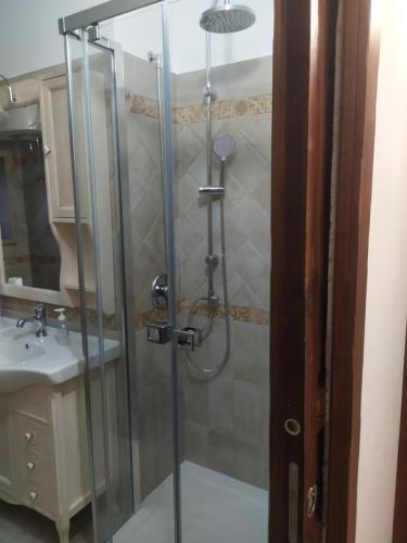 una ducha con una puerta de cristal junto a un lavabo en Il Pittore - Guest House, en Valsinni