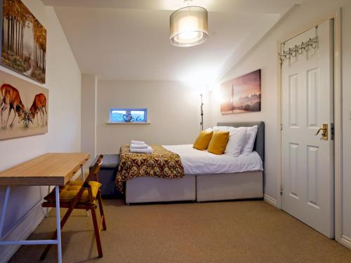 a bedroom with a bed and a desk and a table at Pass the Keys Modern townhouse with secure parking and garden in Cheltenham