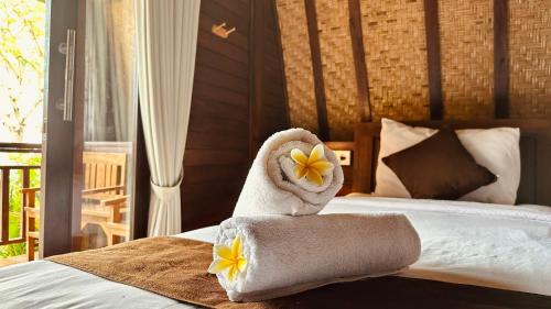 a bedroom with a bed with a towel and flowers on it at Bataran Garden Cottage in Nusa Penida