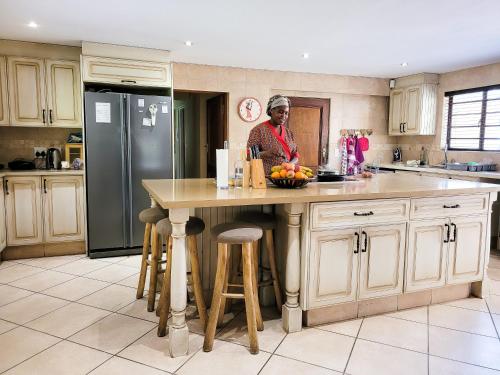 a woman standing at a kitchen island with a bowl of fruit at Blue Hills Lodge in Midrand