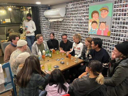 eine Gruppe von Menschen, die in einem Raum an einem Tisch sitzen in der Unterkunft Zzzip Guesthouse in Hongdae in Seoul