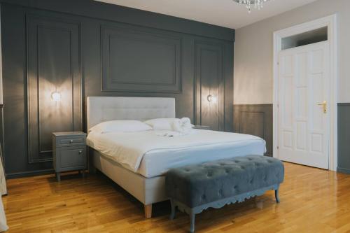 ein Schlafzimmer mit einem weißen Bett und einer blauen Ottomane in der Unterkunft Motel Vila Bakarni in Brčko