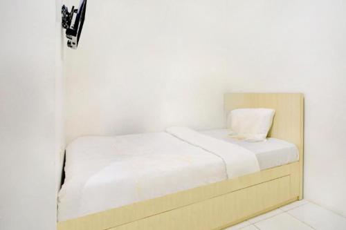 Cama pequeña en habitación blanca en Terrace House, en Tjidantung