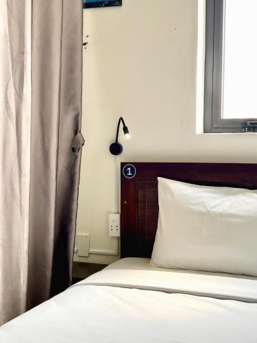 a bed with a wooden headboard and a window at Grand Holiday Hoian Villa in Hoi An