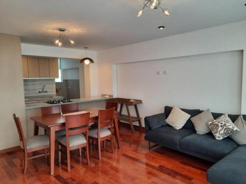 a living room with a couch and a table and a kitchen at Waraqu Wasi Hermoso y acogedor departamento,zona residencial in Cusco