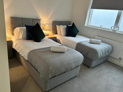 a bedroom with two beds and a ottoman at Luxury 1-Bed Town Centre Platform South Stevenage in Stevenage