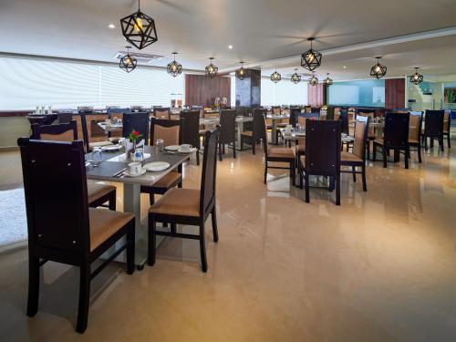 a dining room with tables and chairs in a restaurant at Essentia Premier Hotel, Chennai in Chennai