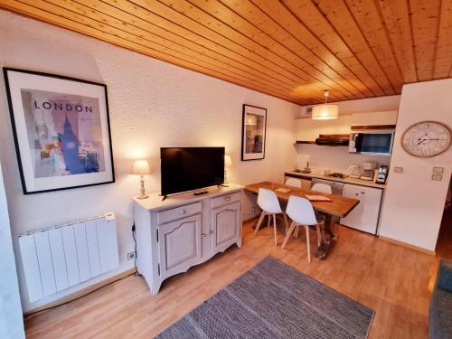 un salon avec une télévision et une table avec des chaises dans l'établissement APPARTEMENT CHAMONIX MONTBLANC 1 à 4 personnes, à Chamonix-Mont-Blanc