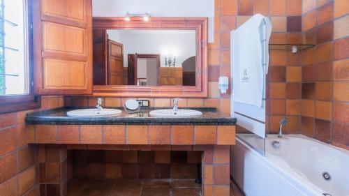 uma casa de banho com 2 lavatórios, uma banheira e um espelho. em Villa Fructus Vejer de la Frontera - El Palmar by Ruralidays em Cádiz