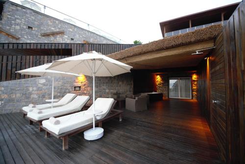 a deck with white lounge chairs and an umbrella at Manaspark Deluxe Hotel in Oludeniz