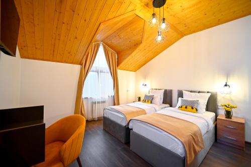 two beds in a room with wooden ceilings and a tv at Aurelia Hotel & Restaurant in Dilijan