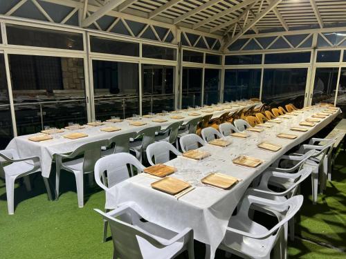 une grande table avec des tables blanches et des chaises blanches dans l'établissement צימר נאשד, à Mas'ada